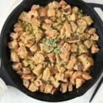Sourdough stuffing in a cast iron skillet and topped with fresh herbs