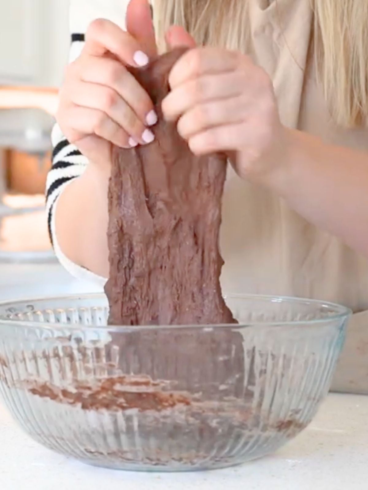 A woman stretch chocolate sourdough dough.