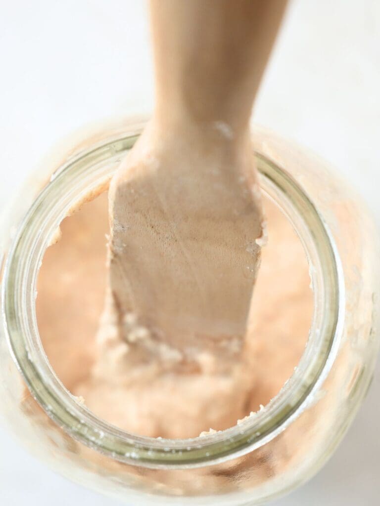 Freshly fed starter in a jar with a wood spoon.