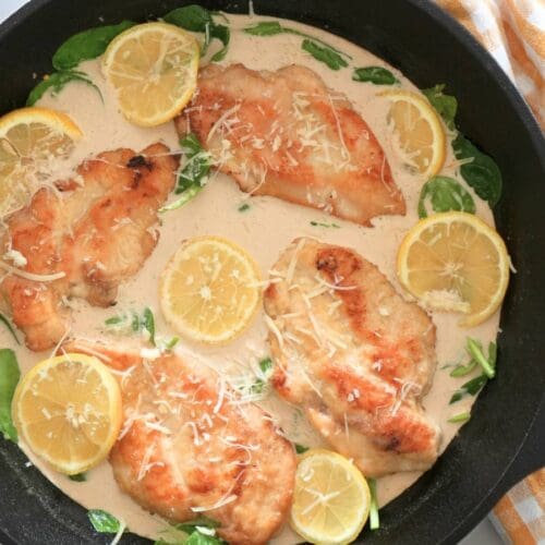 Creamy lemon chicken in cast iron skillet, next to a decorative towel.