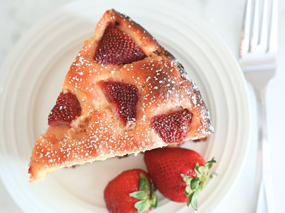 Sourdough strawberry cake slice on a plate next to a fork.
