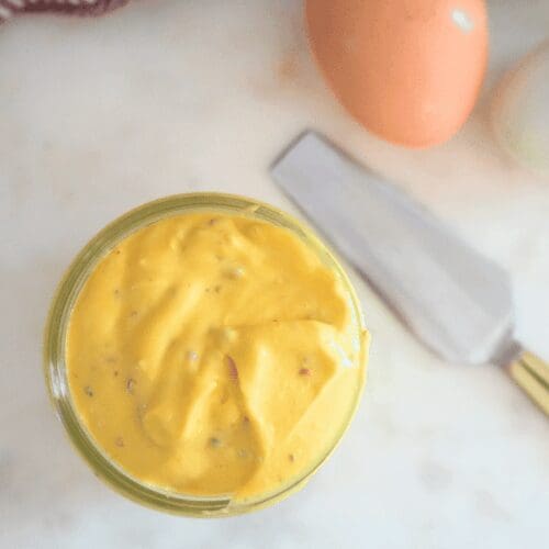 A small jar of French mayonnaise next to a knife and fresh eggs