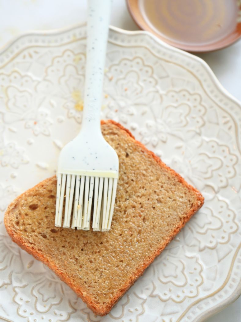 A slice of sourdough bread with and an oiled pastry brush.