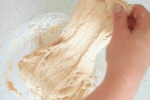 Hands stretching sourdough dough out a glass bowl