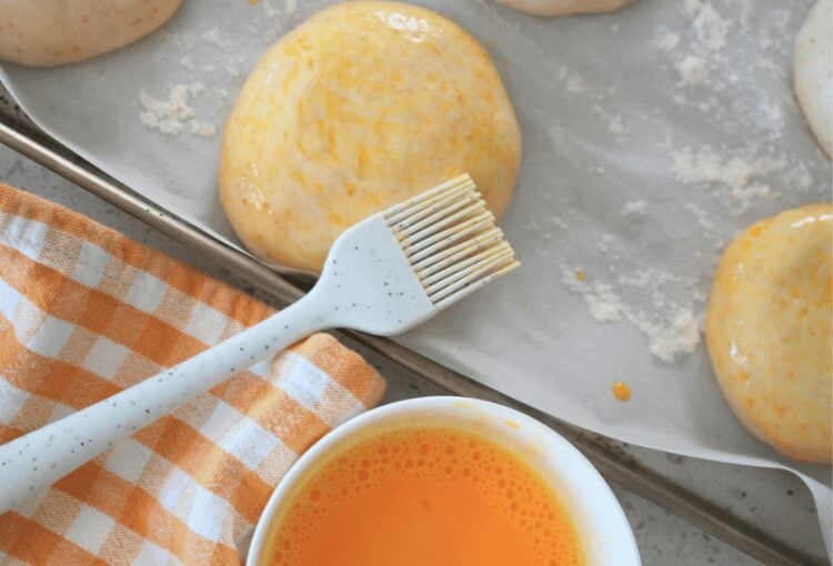Sourdough burger buns dough with egg wash and silicone brush
