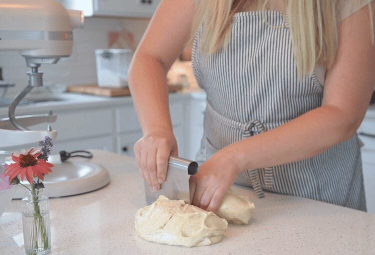 Woman cutting dough with bench scraper