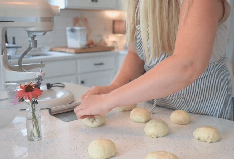 Woman shaping sourdough buns on countertop