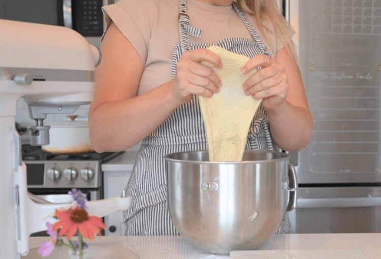 Woman performing the windowpane test on dough