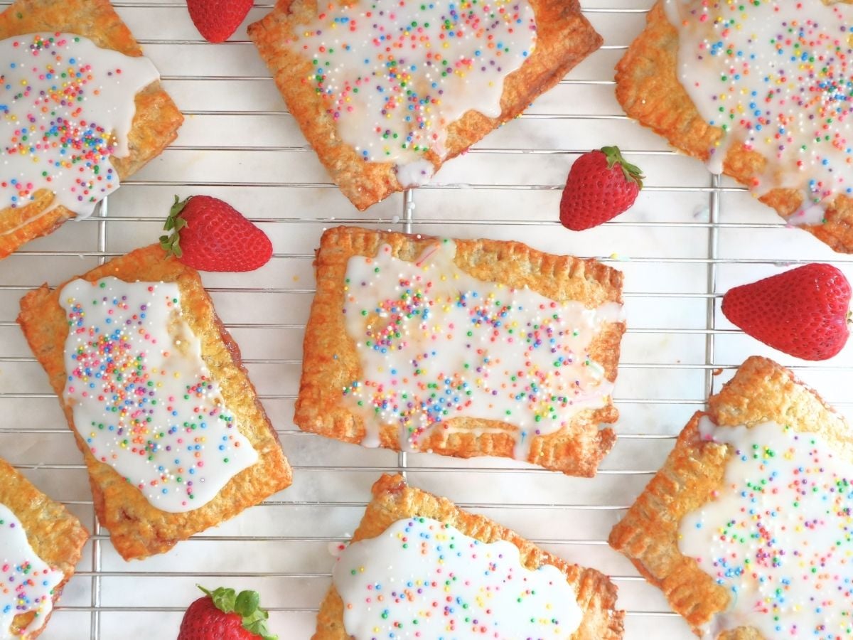 Strawberry sourdough Pop Tarts and fresh berries on a cooling rack.