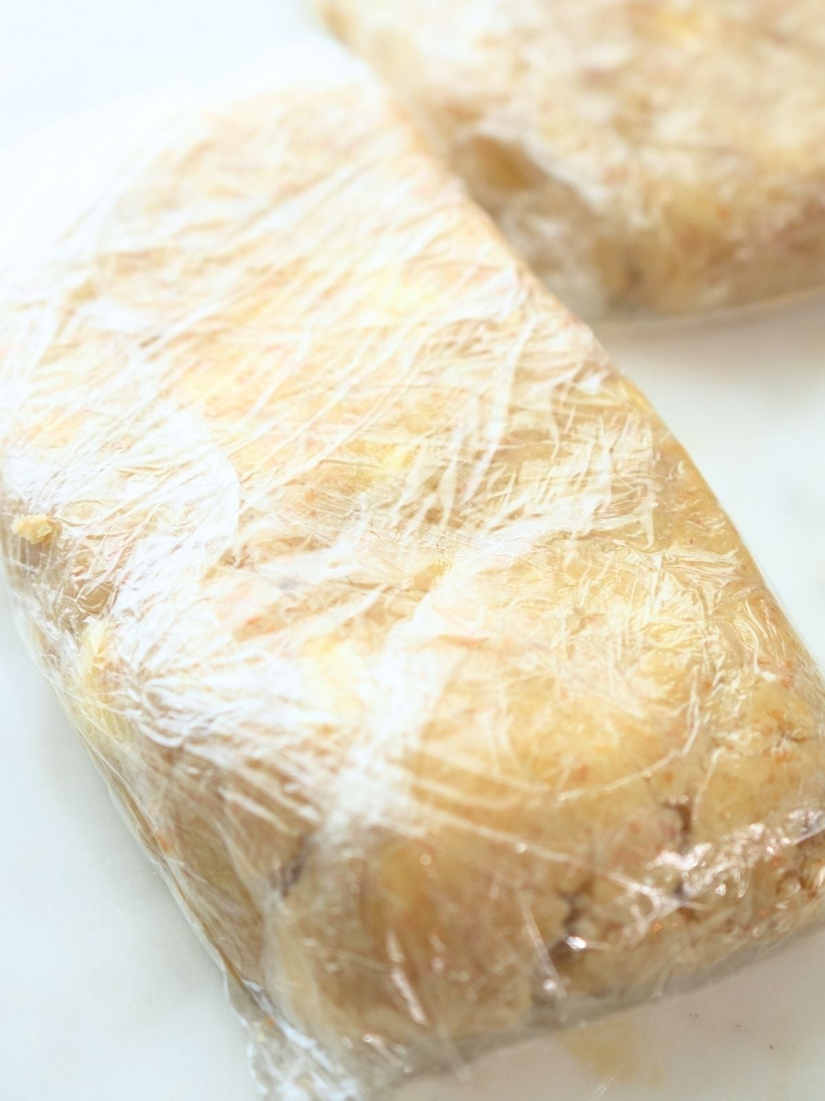Pie dough shaped into a rectangle and wrapped in plastic wrap.