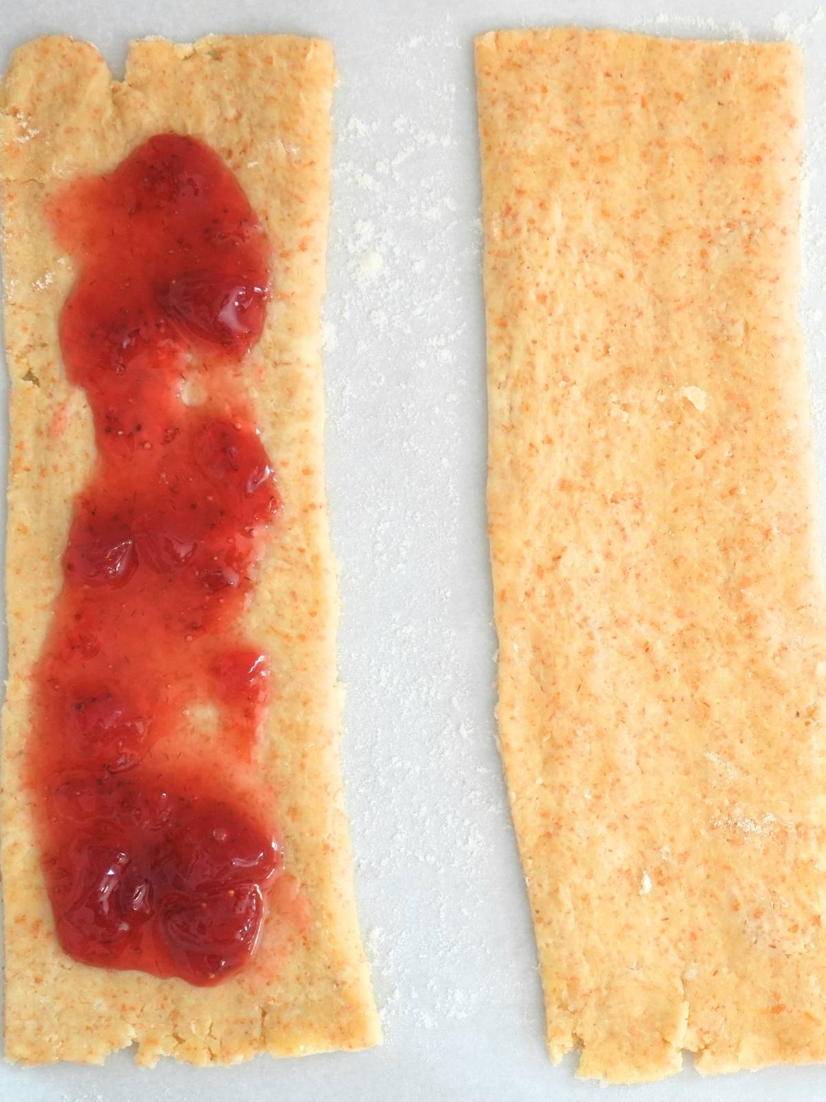 Two slices of pie dough with strawberry jam on one piece.