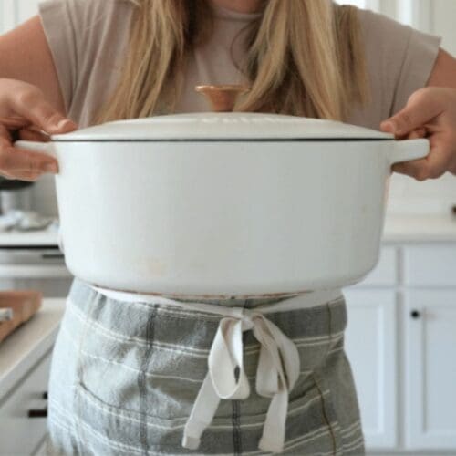 A woman holding a cast iron Dutch oven.