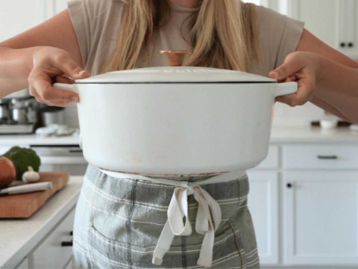 A woman holding a cast iron Dutch oven.