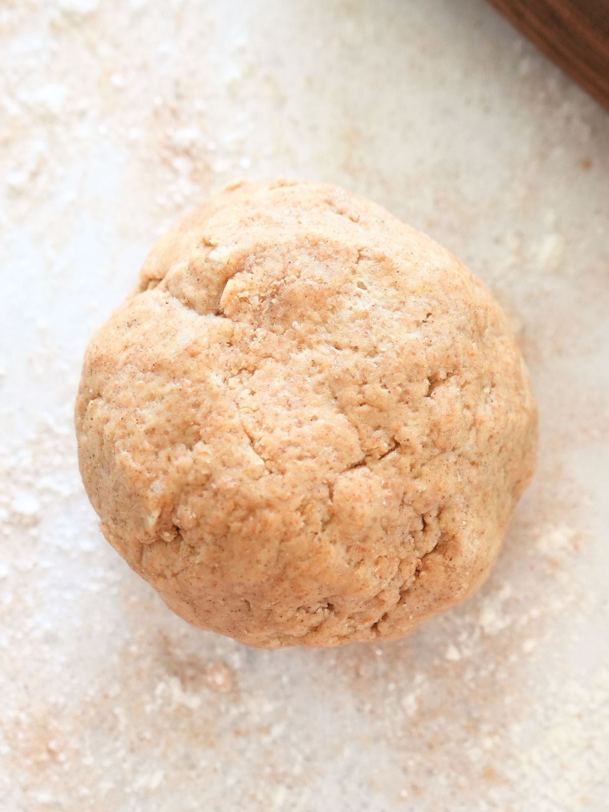 A ball of dough on a surface sprinkles with cinnamon and sugar.