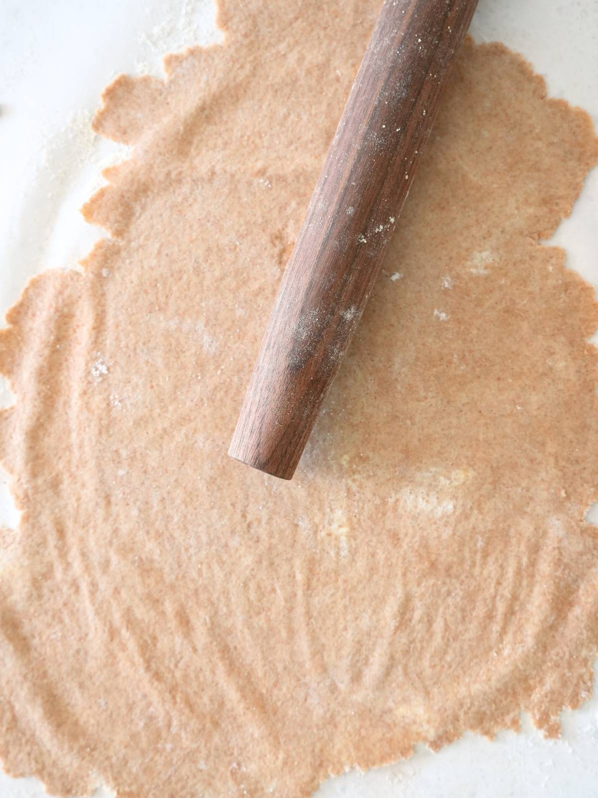 Dough rolled out on parchment paper, shown with a rolling pin.