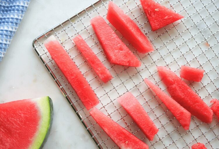 Fresh watermelon on dehydrator tray, shown with watermelon slice and decorative towel
