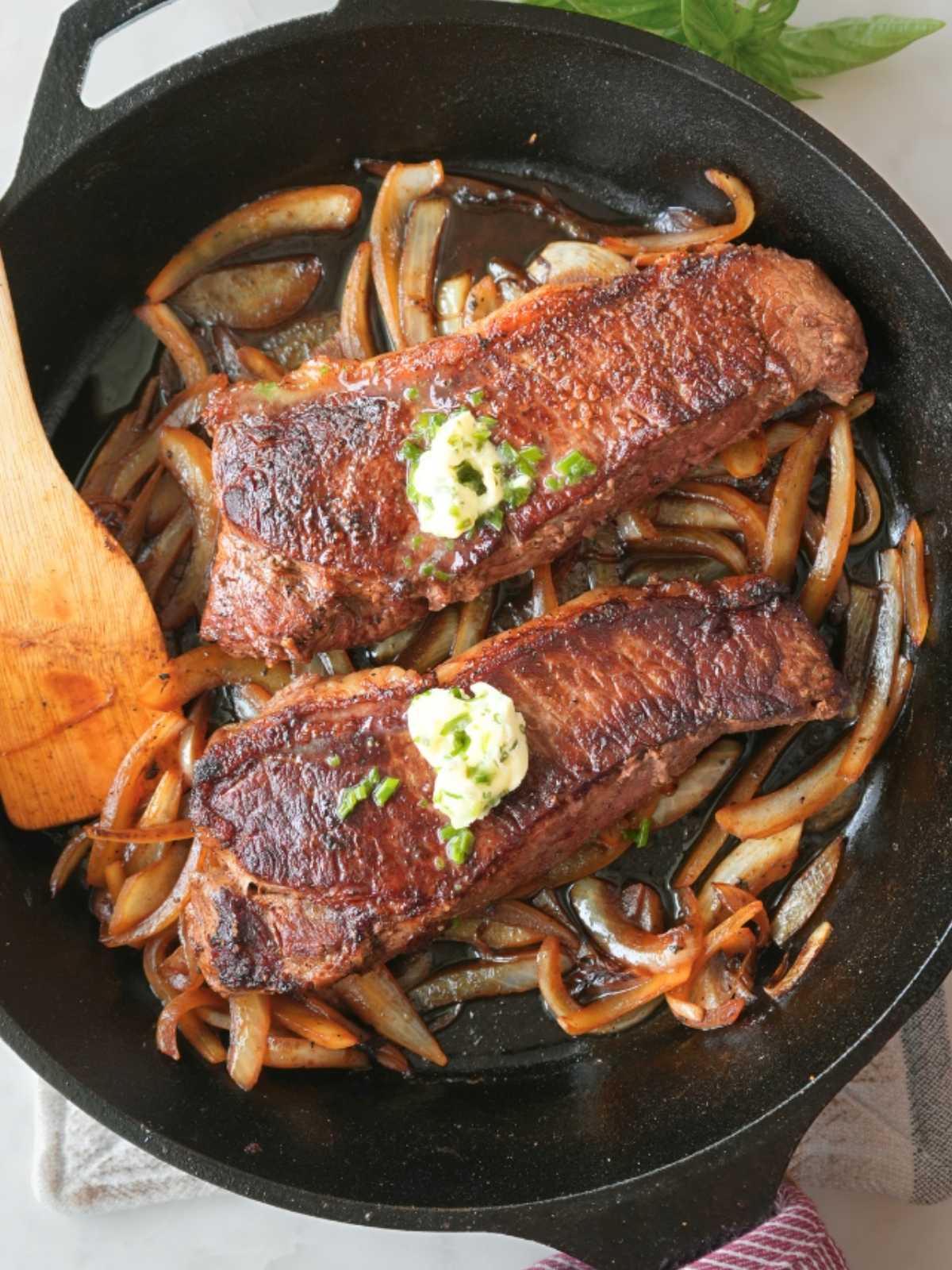 Steaks and onions in a cast iron skillet.