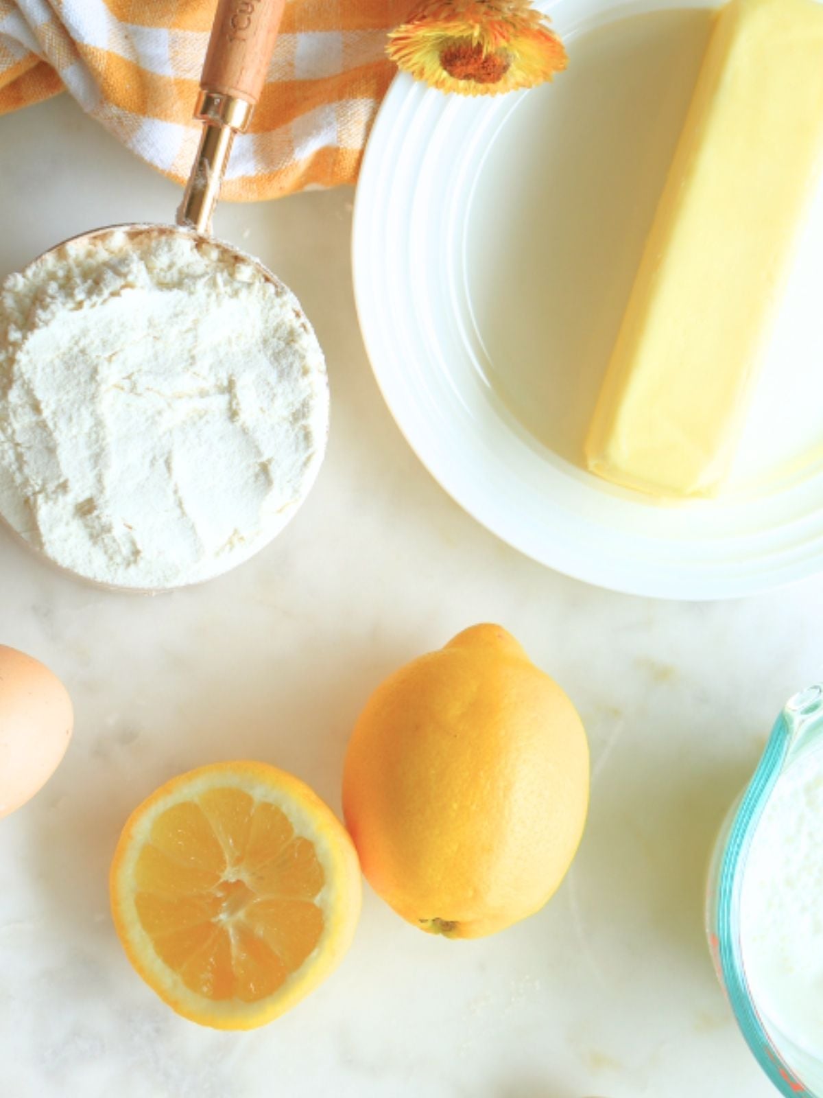 Lemons, flour, and butter on a table.