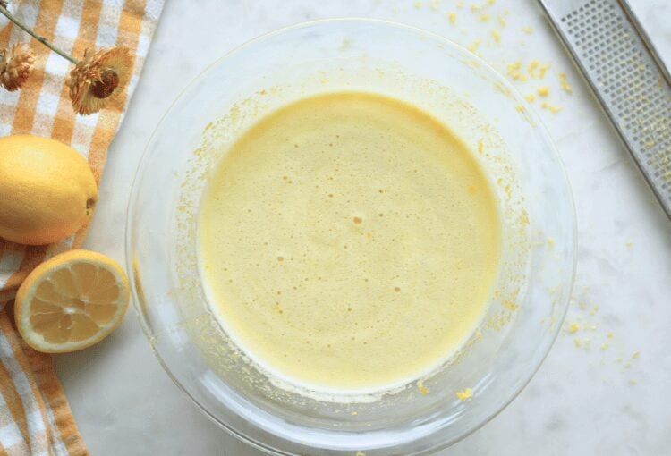 Sourdough lemon bar filling in glass bowl with lemon zest scattered and a lemon zester