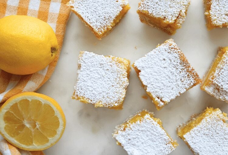 Sourdough lemon bars next to checkered yellow towel and fresh lemons