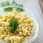 Small glass bowl with cooked millet and cilantro garnish, shown with salt in measuring spoon