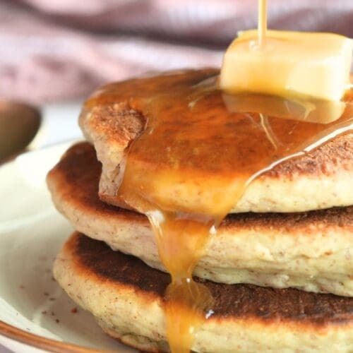 Homemade molasses syrup being poured over a stack of pancakes