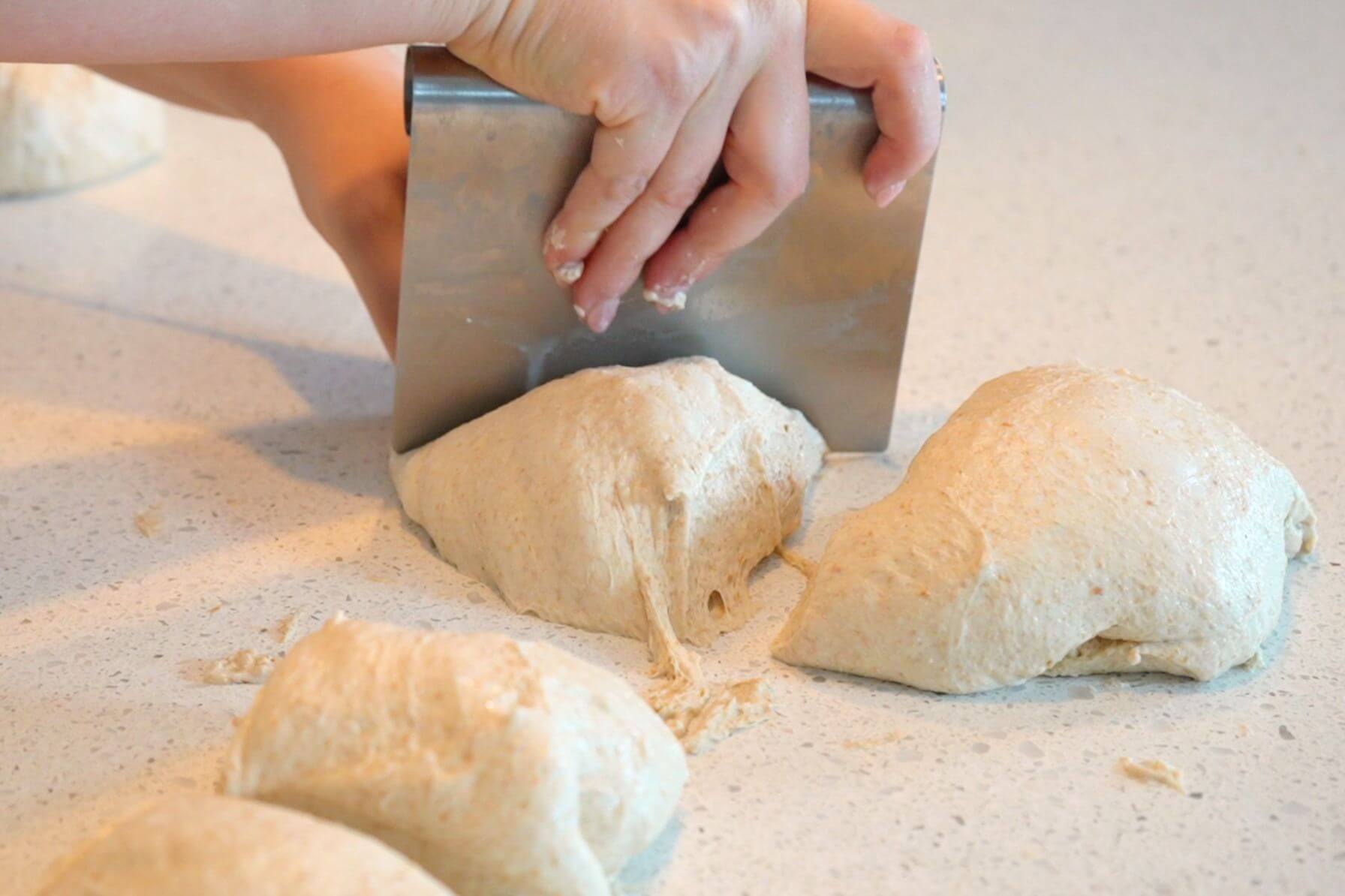 Rebecca using a bench scraper to divide dough