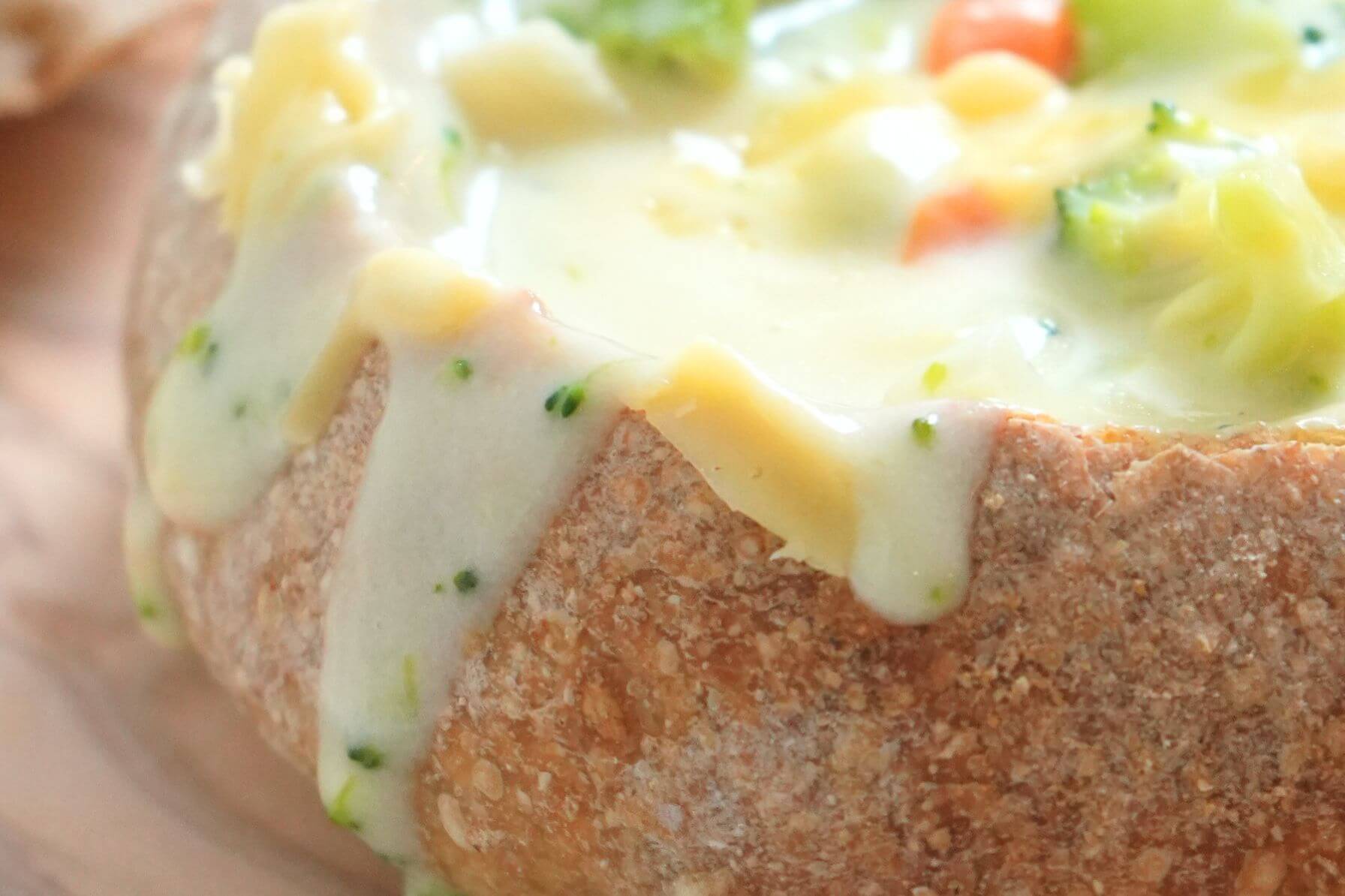 Close up of broccoli soup dripping over the edge of bread bowl