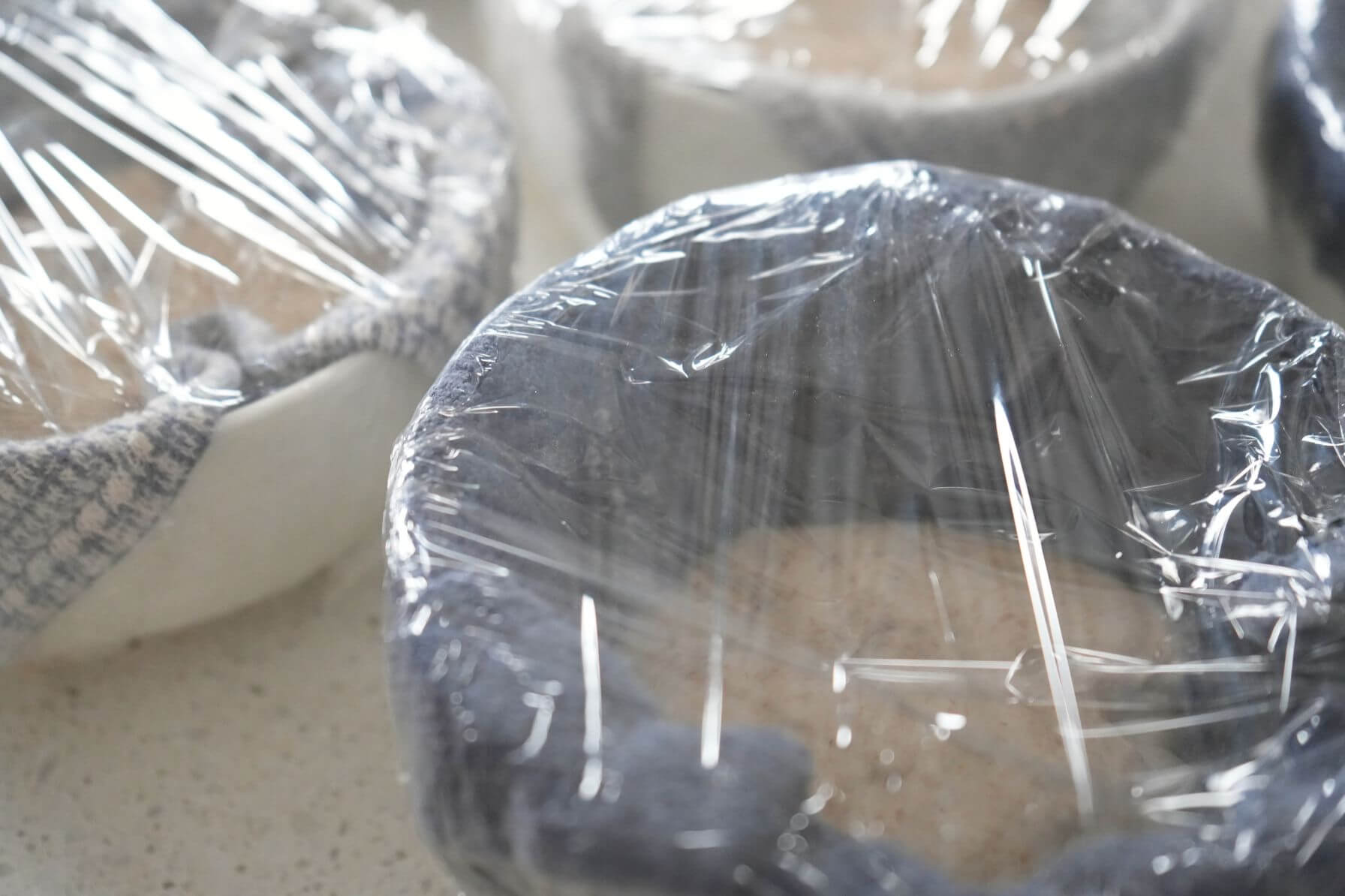 Sourdough bread bowl dough in towel-lined bowl and covered in plastic wrap