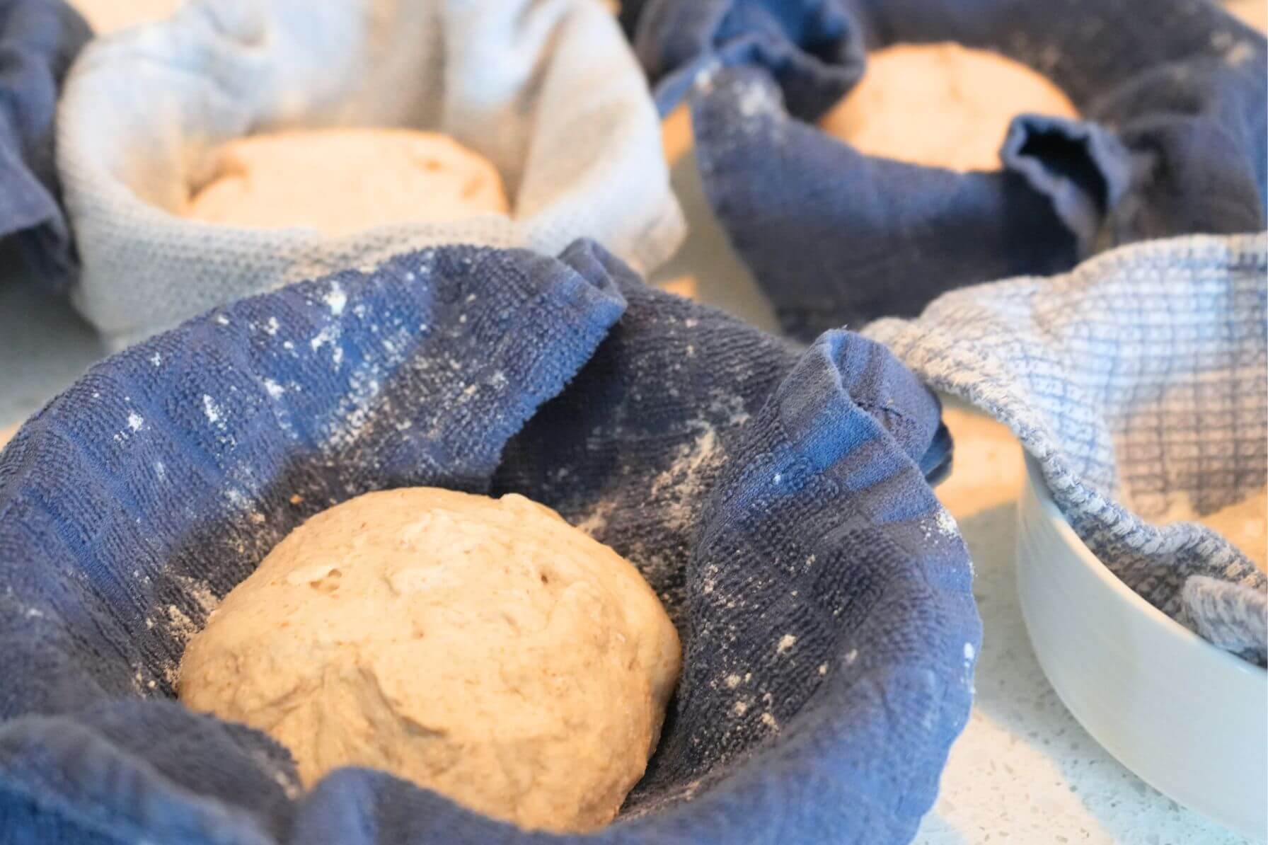 Sourdough bread bowl dough in floured, towel-lined bowl