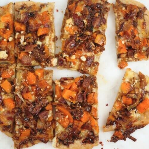 Fall harvest pizza sliced with red pepper flakes scattered around it