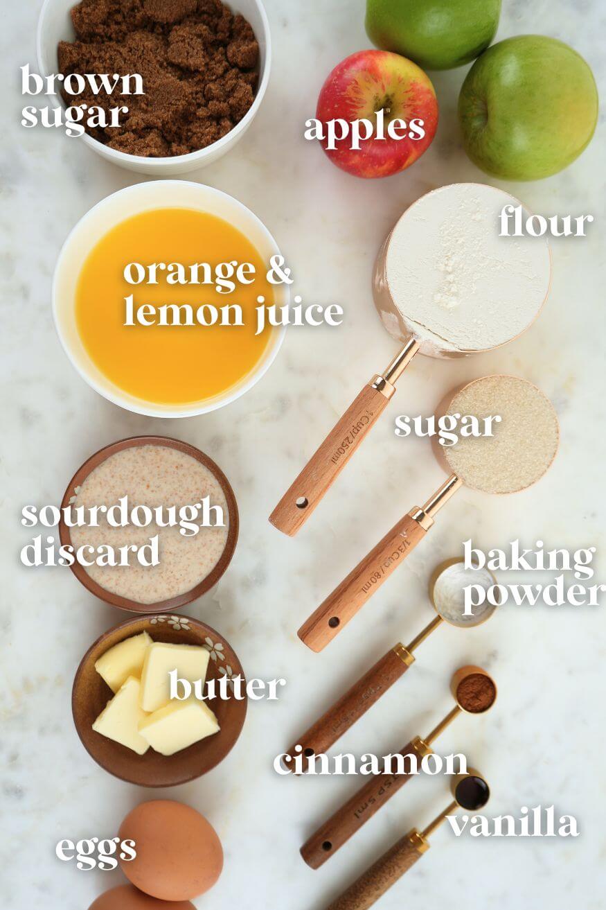Ingredients displayed: brown sugar, orange and lemon juice, sourdough discard, butter, eggs, apple, flour, sugar, baking powder, cinnamon, and vanilla