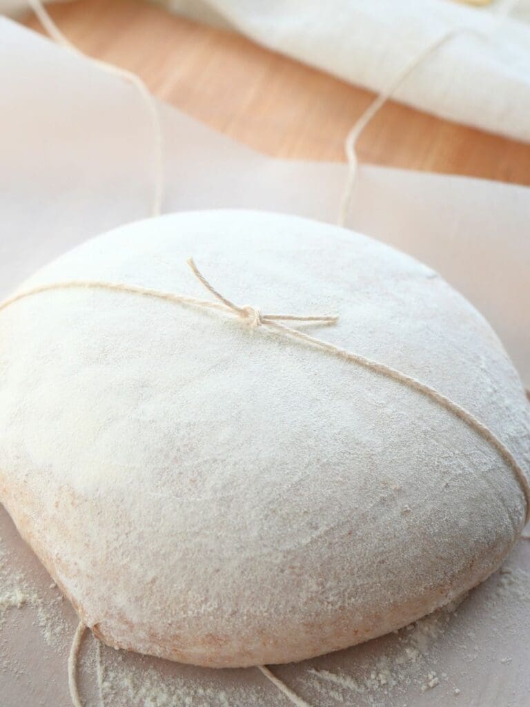Dough with two strings pulled across it and knotted in the center.