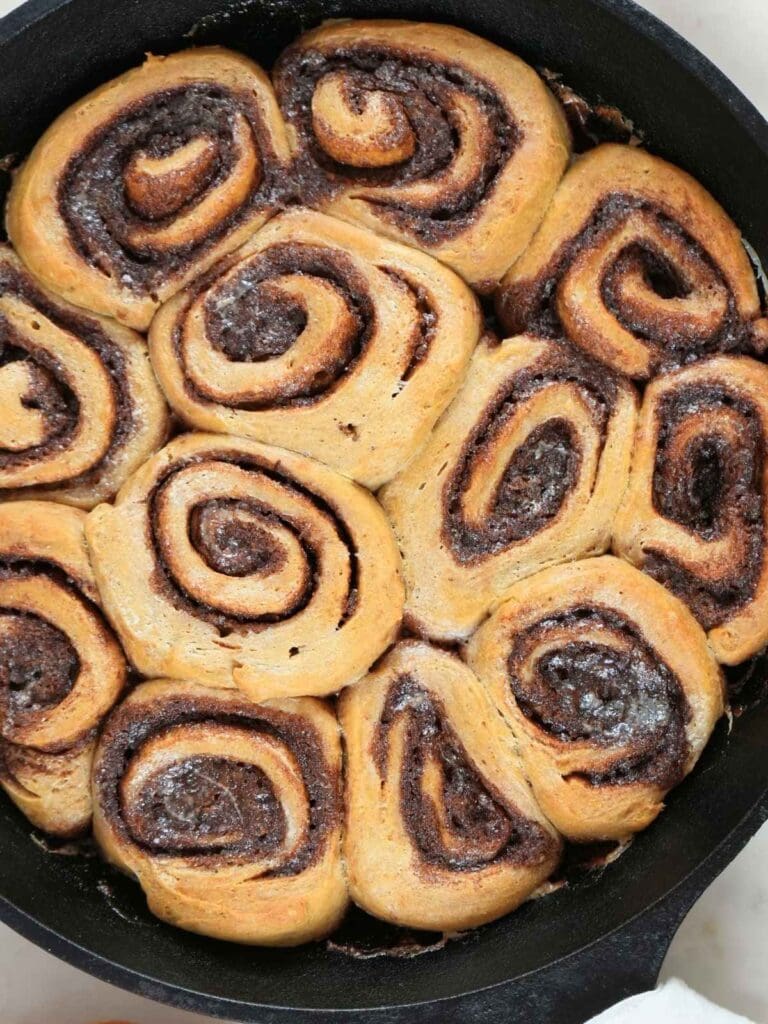 Baked sourdough pumpkin spice cinnamon rolls in a skillet.