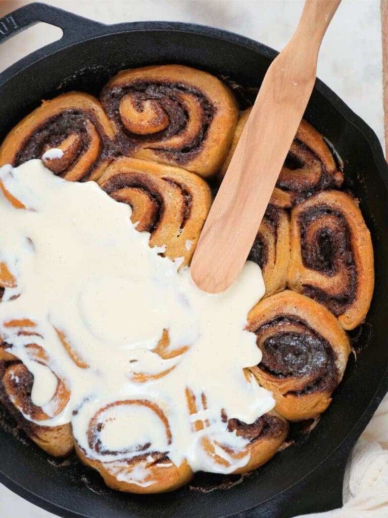 Sourdough pumpkin spice cinnamon rolls half covered with icing.