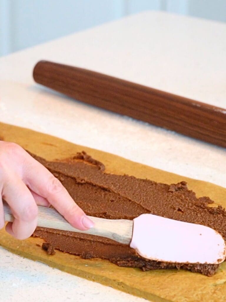 A spatula with cinnamon filling, spreading onto dough.