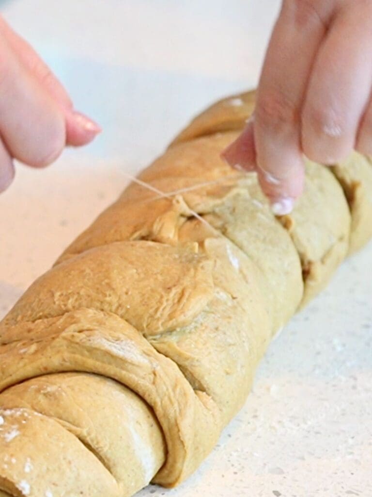 String being used to cut sourdough pumpkin cinnamon rolls.