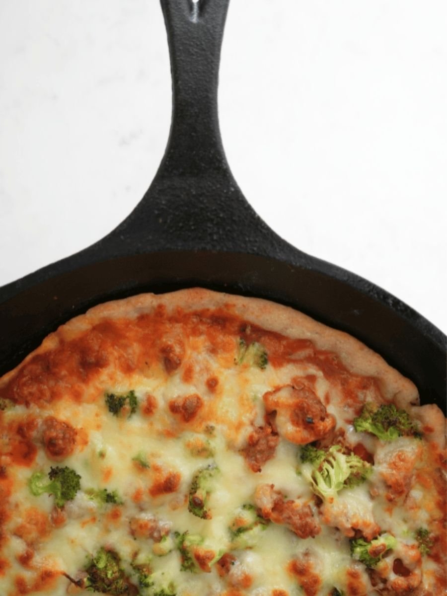Close up of pizza made with sourdough pizza dough, showing the handle of a cast iron skillet
