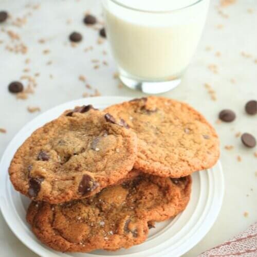 Einkorn chocolate chip cookies on a plate shown with a cup of milk