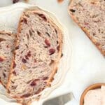 Sliced sourdough cranberry walnut bread on scattered on a plate and counter