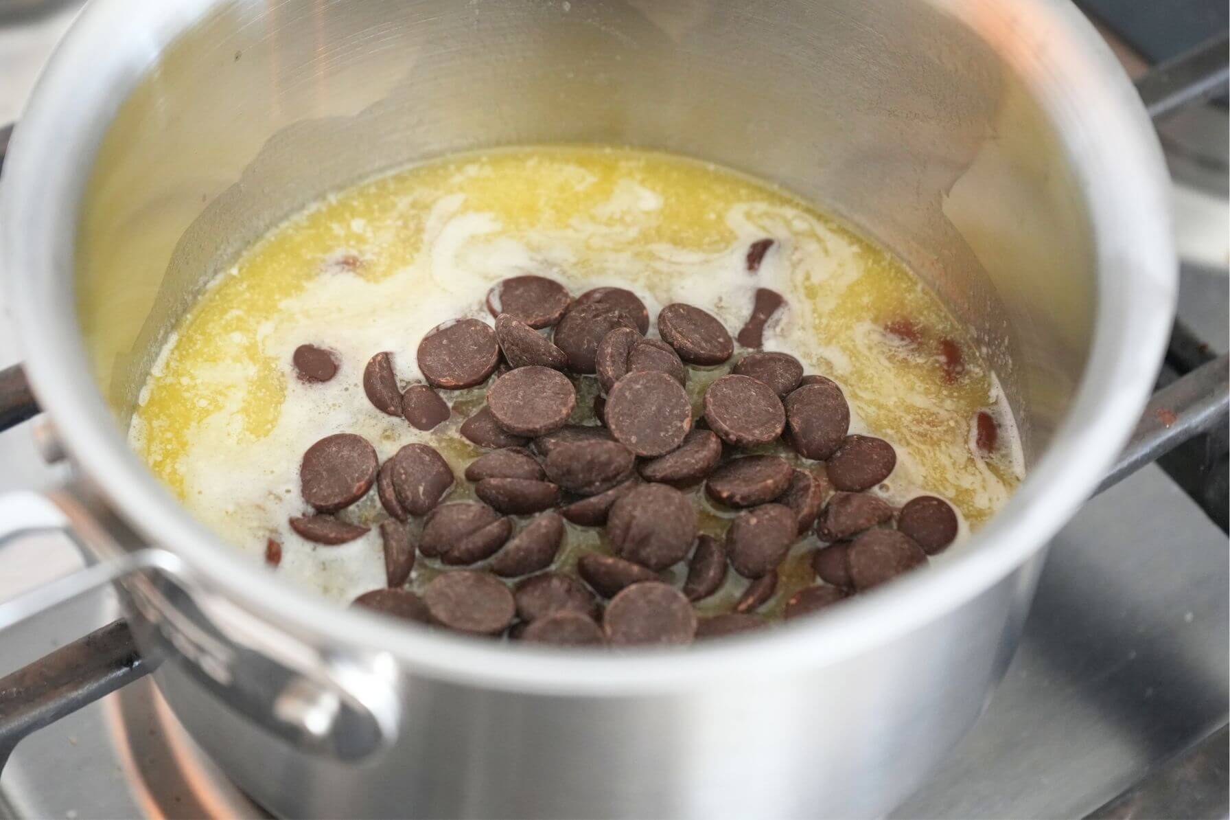 Chocolate chips added to melted butter in a saucepan on the stove.