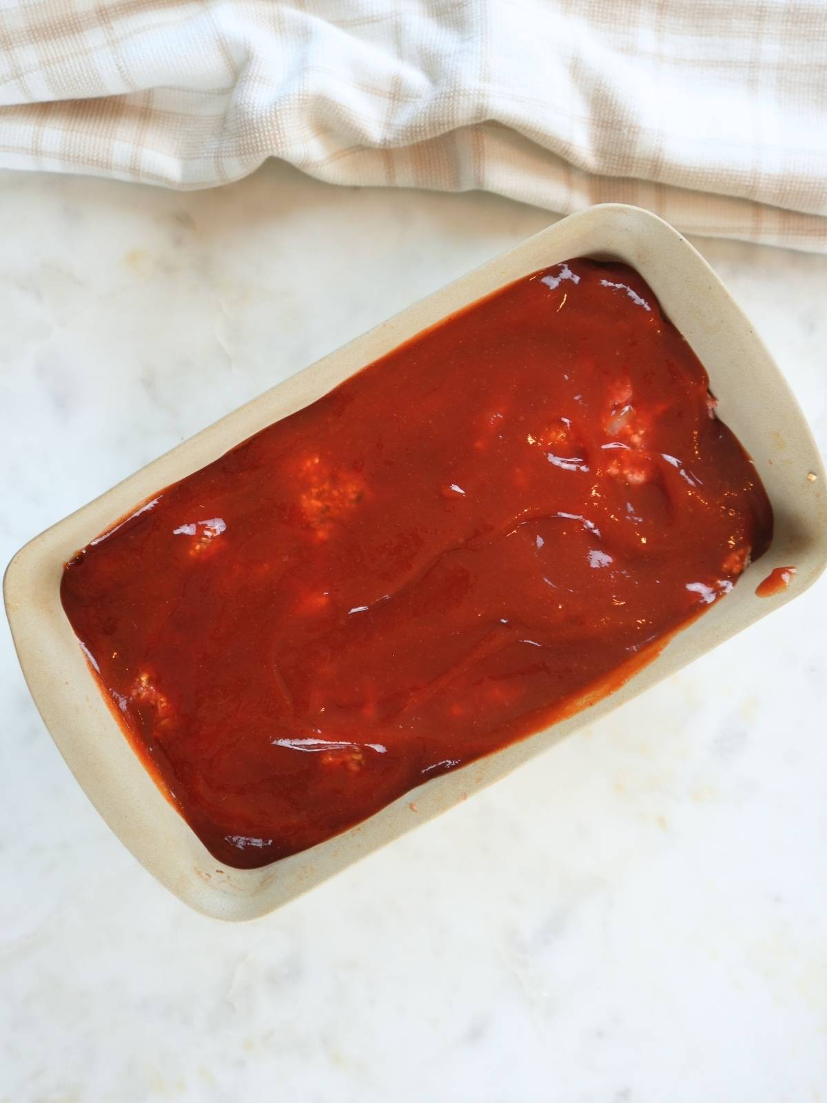 Baking dish with meatloaf covered in hot honey sauce.