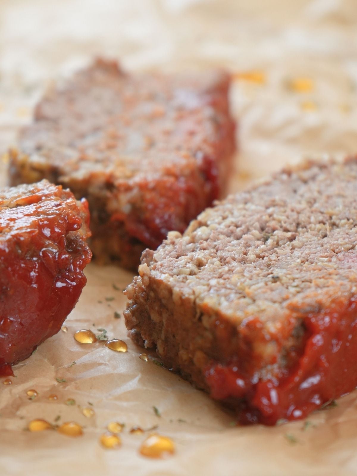 Slices of meatloaf topped with hot honey glaze on parchment paper.