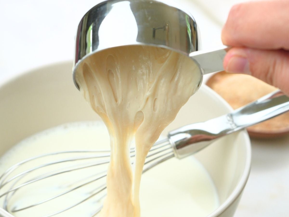 Sourdough stater discard being poured into a bowl of milk.