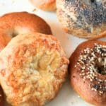 Freshly baked sourdough bagels with golden crusts and toppings.