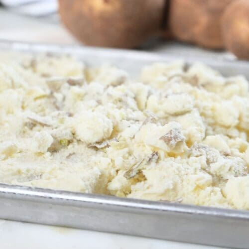 A metal tray filled with crumbled freeze-dried mashed potatoes.