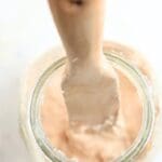 Overhead of a jar of starter stirred with a wooden spurtle