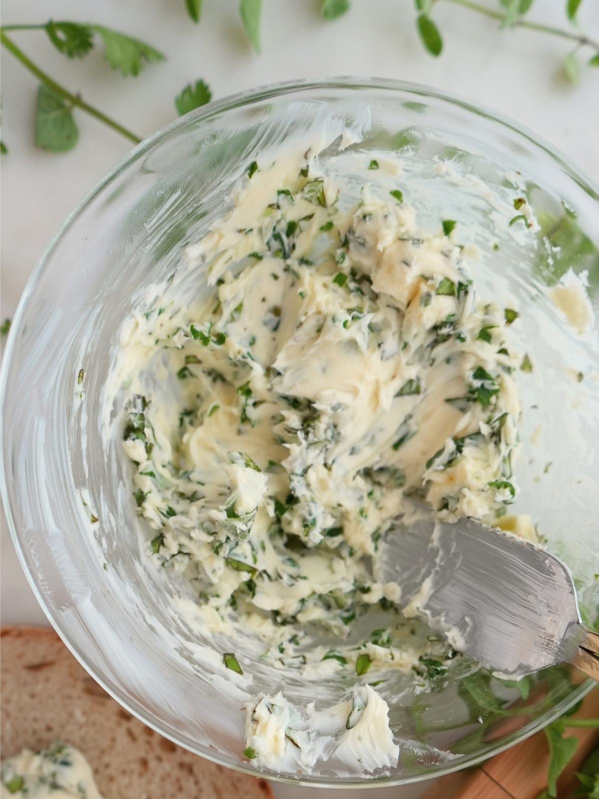 Herb butter ingredients combined in a bowl.