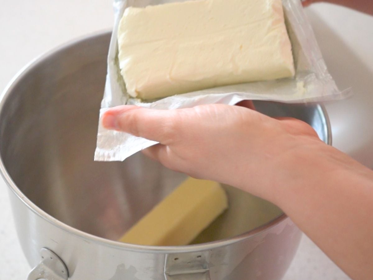 Cream cheese being placed into a stand mixer bowl.