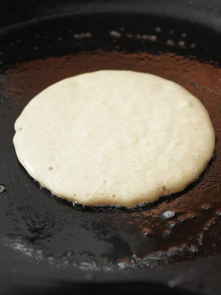 Sourdough discard pancake cooking in skillet.